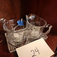 Photo of crystal sugar bowl, cream pitcher, and rectangular tray on wooden shelf.