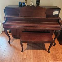 Front view of the Jesse French & Sons upright piano with piano bench in front, showing wood finish and design.