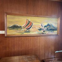 Framed horizontal impressionist oil painting depicting a seascape with sailboats on calm water, hung on a wooden wall.