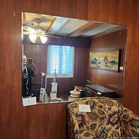 Full view of the large rectangular mirror hung on a wood-paneled wall showing reflective quality and room details.