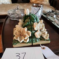 Front view of two ceramic magnolia flower bookends showing detailed floral and leaf design.