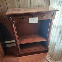 Full view of the dark wood bookcase showing two drawers, open shelf, and decorative details on front corners.