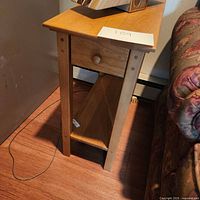 Side view of wooden side table showing drawer and shelf