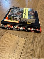Stack of four books including photography and Life magazine compilations on a wooden floor.