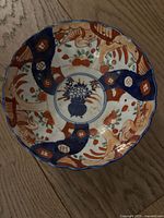 Top-down view showing detailed Imari pattern with floral and geometric designs in blue, red, and orange hues.