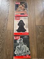 Photo of three vintage LIFE magazines from 1949, stacked on a wooden floor, each with distinct cover images.