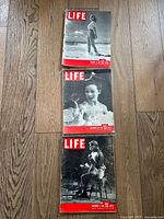 Photo showing three LIFE magazines from 1946 stacked on a wood floor surface. Covers are black and white with distinctive red LIFE logo.