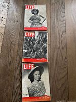 Three vintage Life Magazine issues dated February 23, 1942, March 30, 1942, and January 28, 1943 shown on wooden floor