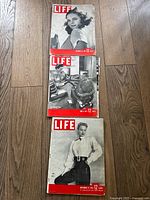 Photo of three Life magazine covers dated December 15 1941, June 9 1941, and November 19 1945 on wooden floor.