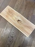 Top-down photo showing the entire rectangular maple wood charcuterie board with prominent wood grain and knot detail, resting on hardwood floor.