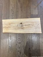 Top view of rectangular maple wood charcuterie board showing natural wood grain and smooth finish, placed on wooden floor.