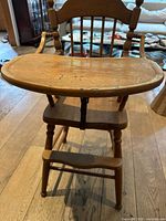 Front view of the wooden baby highchair highlighting the tray surface and seat.