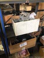 White cardboard box on shelving containing multiple Polonaise figurine ornament boxes and a lower box with the silver mask partially visible
