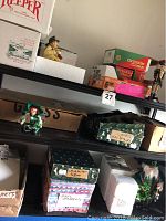 Shelf with Keeper and Crinkle Claus boxes along with small elf figurine and a nutcracker soldier figurine visible
