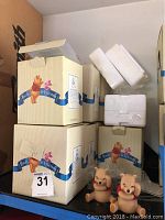 Photo of 3 Pooh and Friends branded boxes with foam inserts visible and two Pooh figurines seated in front, red shirts, beige figurines.