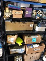 Overall view of shelving with assorted storage boxes, some labeled and empty, various seasonal boxed decorations, and figurines.