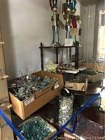 Display of assorted Christmas ornaments including glass items and small white decorations in a jar, on and around a dark wooden furniture piece.