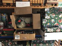 Two cardboard boxes containing multiple small ornaments on a shelf with additional ornament boxes