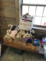 Wide shot of boxes filled with various plush animals including dogs, penguins, and clowns at a wooden wall window.