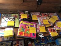 Top-down photo showing multiple origami kits and paper packs arranged on a wooden surface.