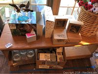 Wide view showing eagle figurine, boxed butterfly ornaments, small doll, glass jars and more on wooden shelf