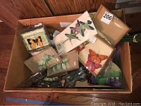 Box containing multiple dragonfly and butterfly decorations with assorted colors and shapes.