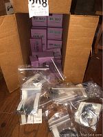 Cardboard box containing approximately 12 purple “Anne Dilker Fine Silver” presentation boxes and several plastic bags of bracelets.