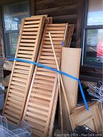 Wooden shutter panels and some wooden boards tied with blue tape leaning against a wall on a porch.