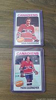 Front side of two hockey cards showing players Doug Risebrough (Center) and Yvon Cournoyer (Right Wing) in Montreal Canadiens uniforms, placed one above the other in protective sleeves.