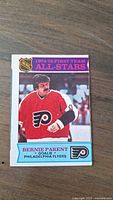 Front of the 1974-75 Bernie Parent OPC First Team All Star hockey card showing Bernie Parent in Philadelphia Flyers uniform.