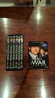 Overall view of Foyle's War DVD boxes series 1 to 7 laid out on a wooden table.