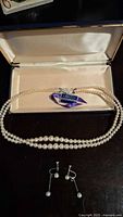 Full view of the pearl necklace and matching earrings in the display box showing the necklace clasp and earrings below.