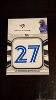 Front of the Vladimir Guerrero Jr. medallion jersey number baseball card featuring the number 27 in blue and white, with Toronto Blue Jays logos and text.