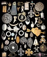 Top-down view of a full collection of various metal charms and pendants laid out on a black background showing varied designs and shapes.