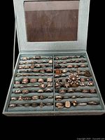 Two-panel ring display tray containing multiple rows of assorted silver-tone rings in various designs and sizes