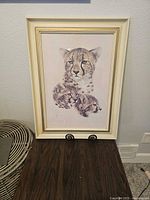 Full view of framed leopard family picture on a shelf.