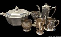 Group photo of six vintage silver and silver-plated serving pieces on black background.