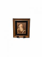 Full view of the framed signed oil painting of an elderly man reading, shown on an easel stand.