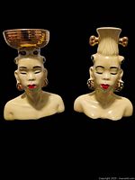 Front view of the pair of vintage Nubian ceramic head vases showing detailed facial features, red lips, and gold accents on headdresses.