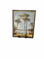 Full view of the framed vintage painting showing two huts, tall trees, two figures by a lake, and the sky.