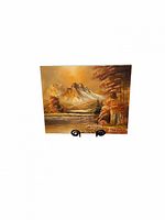 Vintage oil painting on canvas featuring a mountain range, lake, and forest in warm orange tones, displayed on a small stand.