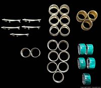 All items arranged on black background showing multiple sets of vintage napkin rings and spoon rests.