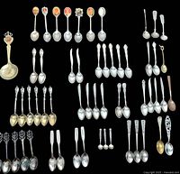 Multiple sets of vintage silver spoons arranged on black background showing various styles and designs