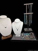 Overall display of jewelry on two busts and tray