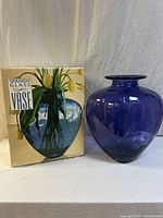 Cobalt blue glass vase with rounded shape and flared rim next to original box with picture and Spanish Glass Vase label.