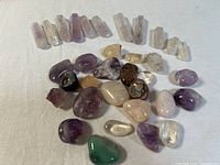 Full view of polished tumbled stones including amethyst, rose quartz, citrine, clear quartz, agate, and green aventurine arranged on fabric.