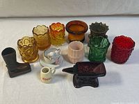 Photo showing all 12 miniature glass and ceramic novelty items including colorful pressed glass toothpick holders, ceramic boot, cow creamer, and black glass anvil.