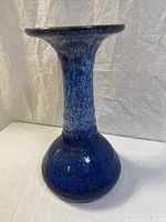 Front view of the tall ceramic vase showing the cobalt blue drip glaze and bulbous base.