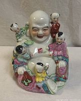 Front view of Laughing Buddha figurine with five children showing facial details and colorful robes.
