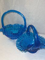 Both vintage blue hobnail glass baskets shown side by side on a white backdrop